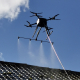 drone équipé d'un système de pulvérisation permettant le démoussage ou le nettoyage des toits