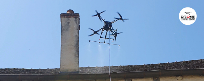 Photographie d'un drone réalisant un démoussage de toiture par drone